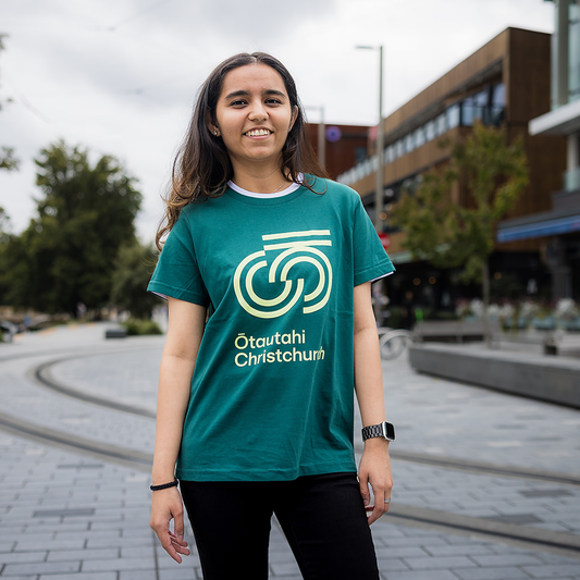 Person wearing a green t-shirt with a logo and text, standing outdoors.